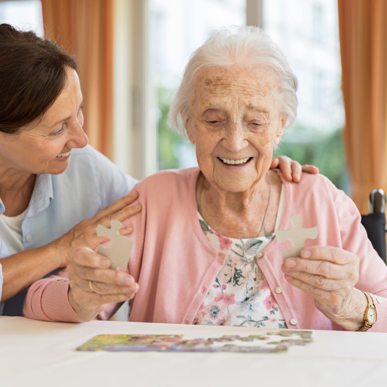 Happy senior woman in wheelchair with caregiver